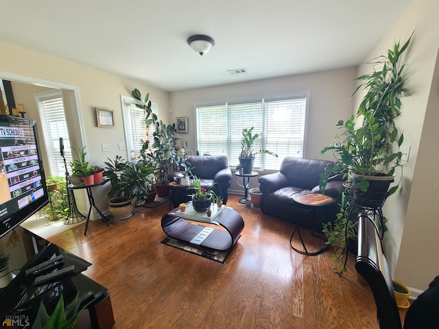 living area featuring baseboards, visible vents, and wood finished floors