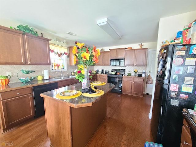 kitchen featuring a sink, dark wood-style floors, visible vents, black appliances, and decorative backsplash