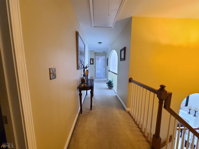 hall with light carpet, baseboards, attic access, and an upstairs landing