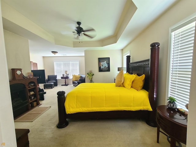 bedroom featuring ceiling fan, carpet flooring, and a raised ceiling