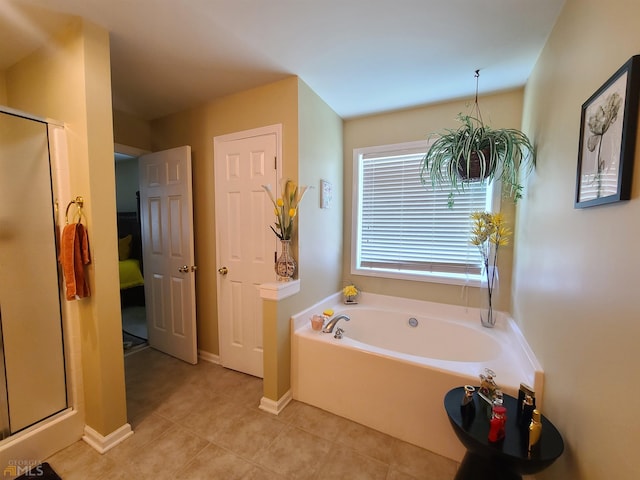 bathroom featuring tile patterned flooring, baseboards, a garden tub, and a shower stall