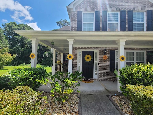 entrance to property with covered porch and brick siding