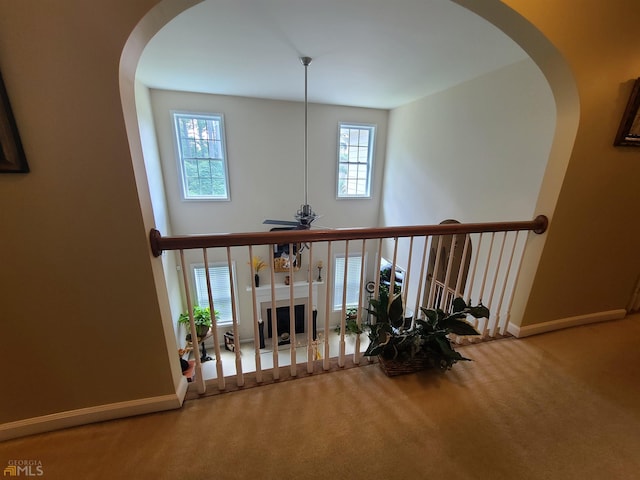interior space featuring carpet, baseboards, arched walkways, visible vents, and ceiling fan