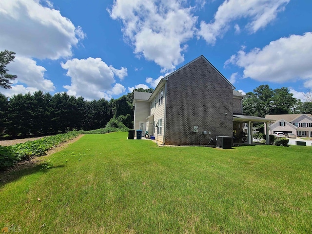 view of side of home with central air condition unit, brick siding, and a yard