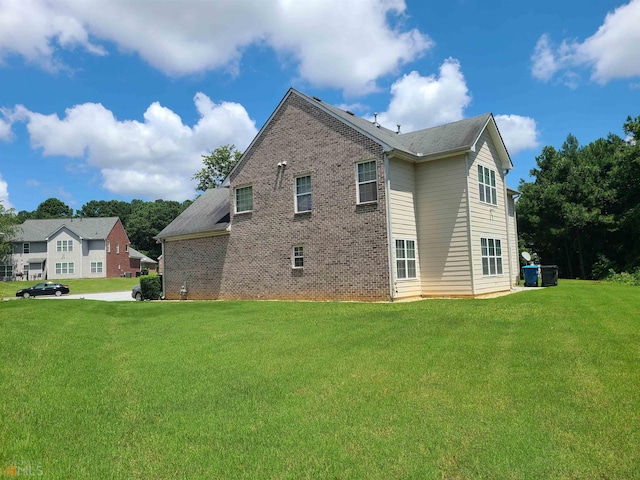 view of side of home with brick siding and a yard