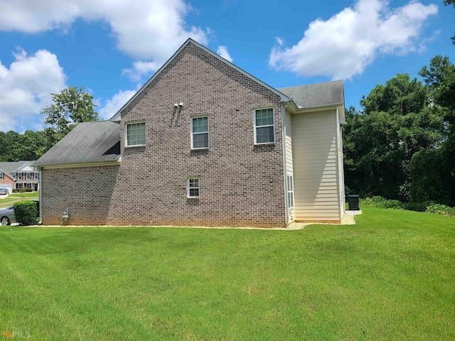 view of side of property featuring brick siding and a yard