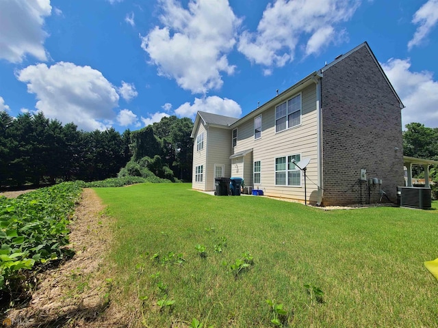 rear view of property featuring a lawn and cooling unit