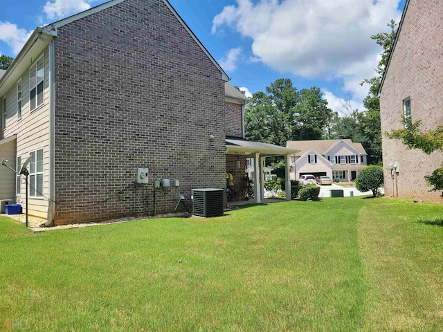 view of side of home with brick siding, central AC, and a lawn