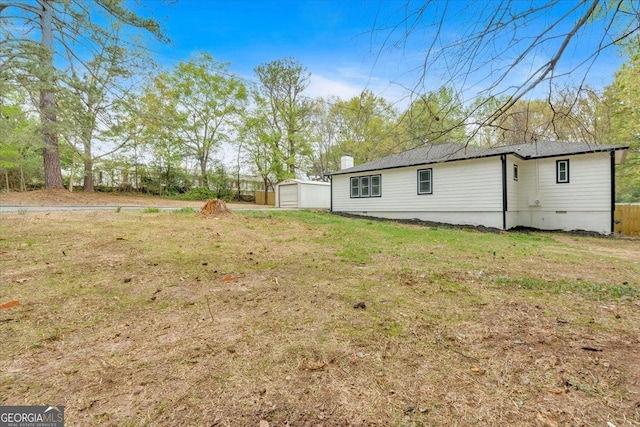 rear view of house featuring an outdoor structure, a chimney, crawl space, a garage, and a yard