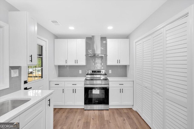 kitchen featuring light countertops, light wood-style floors, stainless steel range with electric cooktop, and wall chimney range hood