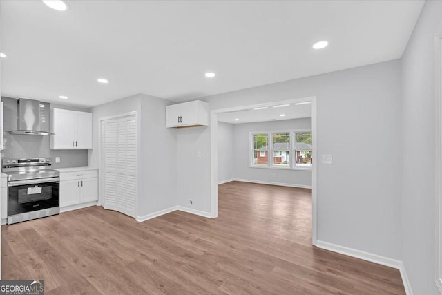 kitchen featuring white cabinetry, light wood finished floors, wall chimney exhaust hood, and stainless steel range with electric stovetop