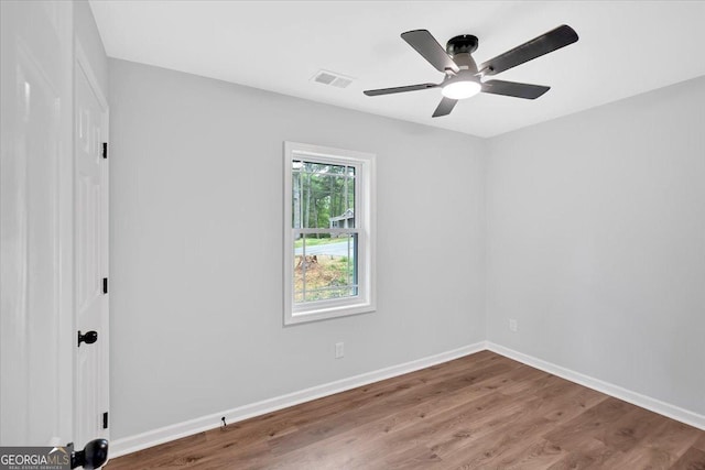 spare room with wood finished floors, baseboards, and visible vents