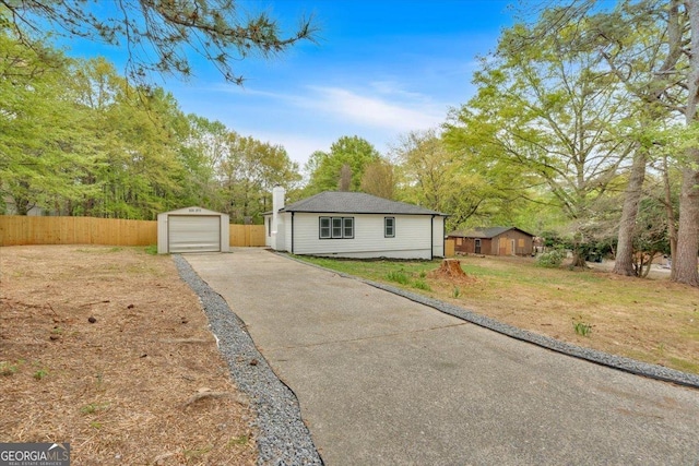 view of front of property with aphalt driveway, fence, an outbuilding, and a detached garage