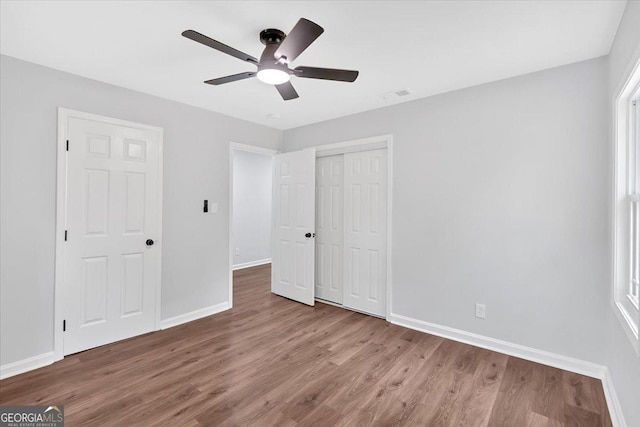 unfurnished bedroom featuring a closet, visible vents, baseboards, and wood finished floors