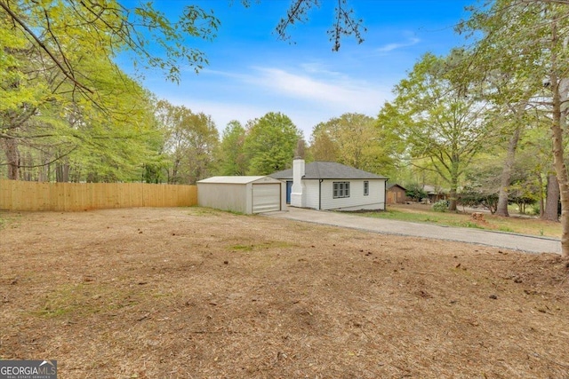 view of yard with driveway, a garage, and fence
