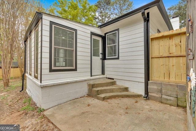 view of exterior entry featuring a patio and fence