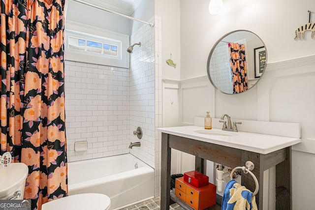 full bath featuring a decorative wall, toilet, shower / bath combo, a sink, and wainscoting