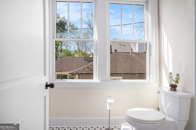 bathroom with toilet, a wealth of natural light, and baseboards