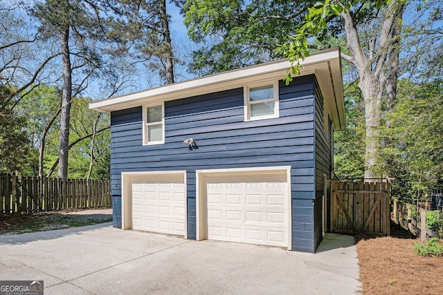 garage featuring driveway and fence