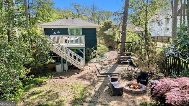 back of house featuring an outdoor fire pit, a wooden deck, fence, and stairs