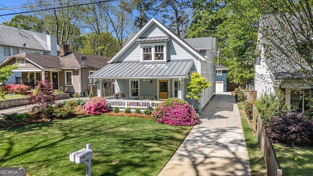 view of front of property featuring a porch, metal roof, fence, a front lawn, and a standing seam roof
