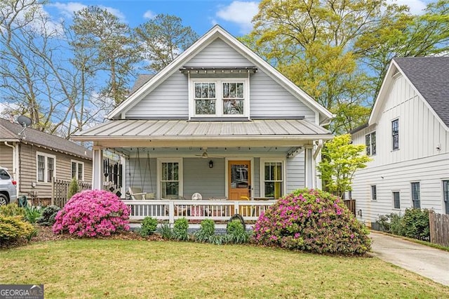 view of front facade featuring a standing seam roof, a porch, metal roof, and a front lawn