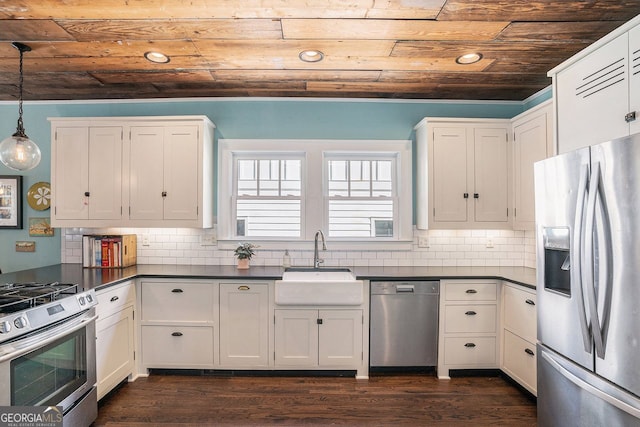 kitchen with dark countertops, white cabinets, stainless steel appliances, wood ceiling, and a sink