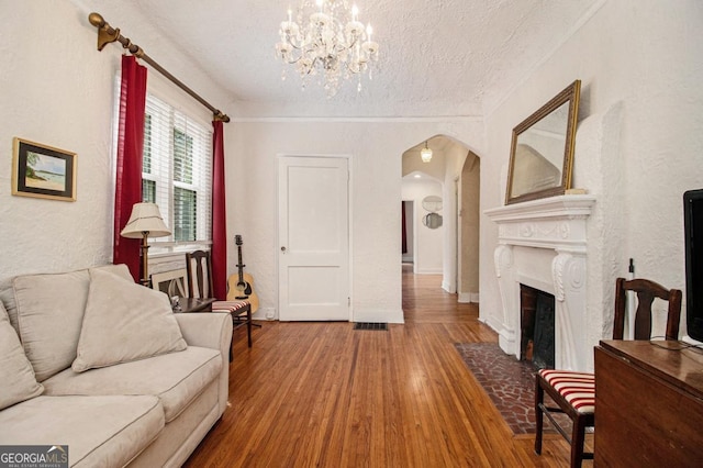 650 Somerset Ter NE, Atlanta, GA 30306 - living room with arched walkways, wood finished floors, a textured ceiling, a chandelier, and a fireplace with flush hearth
