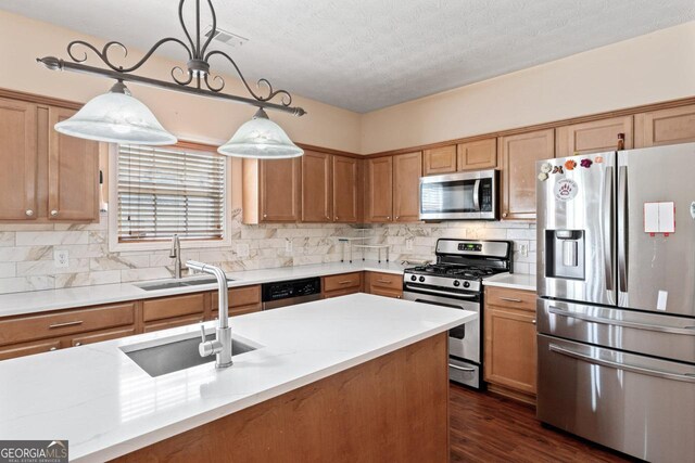 kitchen with a sink, appliances with stainless steel finishes, pendant lighting, and dark wood-type flooring