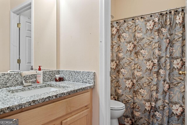 bathroom with a shower with shower curtain, toilet, and vanity
