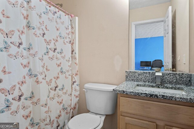 bathroom with toilet, vanity, and a shower with shower curtain