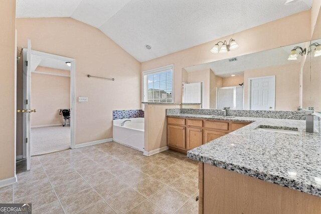 bathroom with tile patterned flooring, vanity, lofted ceiling, a stall shower, and a garden tub