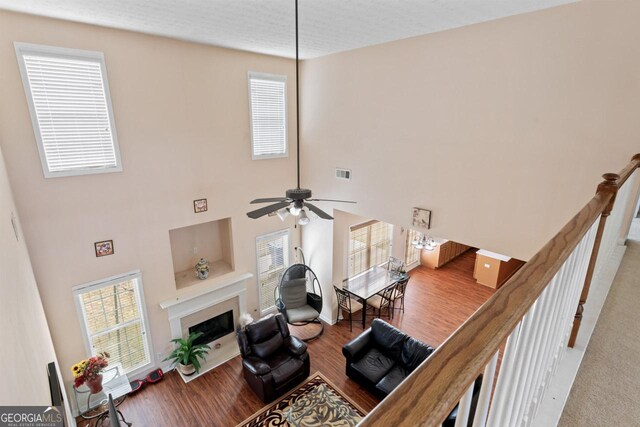 living room featuring wood finished floors, a wealth of natural light, a fireplace, and visible vents
