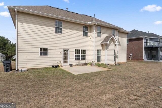back of house featuring a lawn, a patio area, and roof with shingles