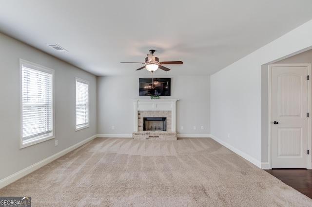 unfurnished living room with baseboards, ceiling fan, visible vents, and a brick fireplace
