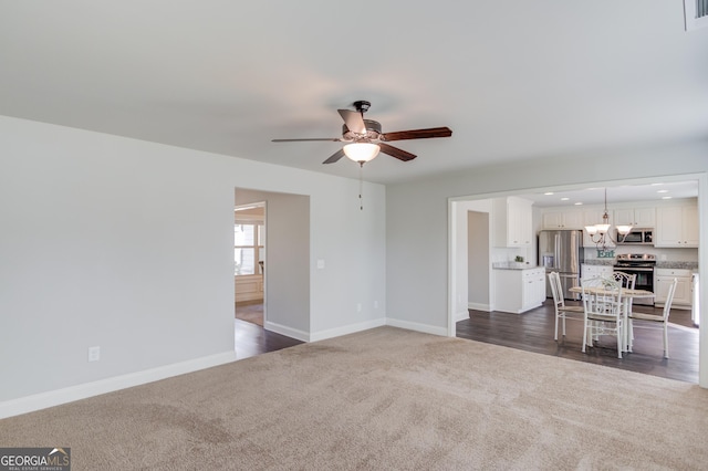unfurnished living room with baseboards, recessed lighting, ceiling fan with notable chandelier, and dark colored carpet