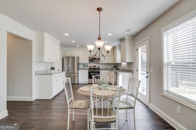 dining room featuring dark wood-style flooring, plenty of natural light, baseboards, and a chandelier