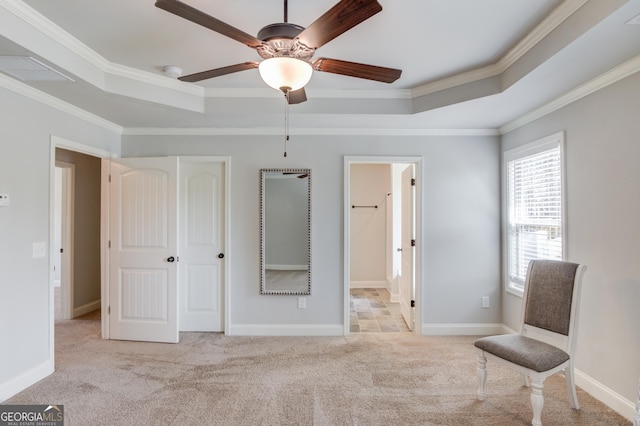 unfurnished bedroom featuring carpet flooring, a tray ceiling, baseboards, and crown molding