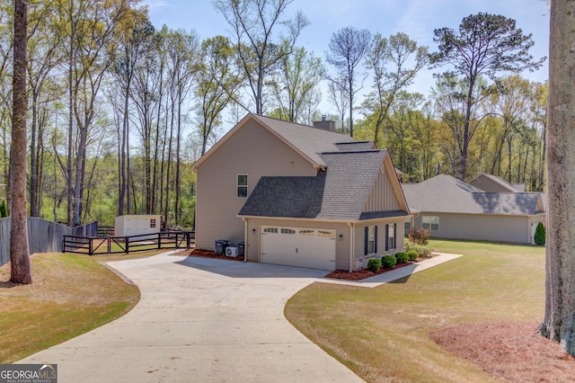 view of home's exterior featuring fence, an attached garage, roof with shingles, driveway, and a yard