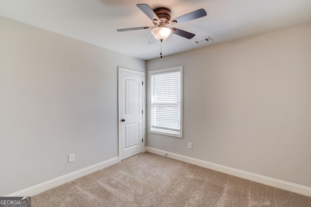 empty room featuring baseboards, ceiling fan, visible vents, and light carpet