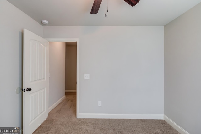 spare room with baseboards, light colored carpet, and ceiling fan