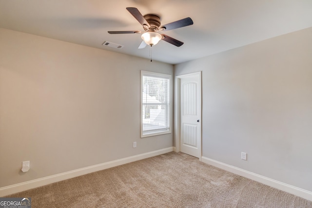 unfurnished room featuring baseboards, visible vents, a ceiling fan, and light colored carpet