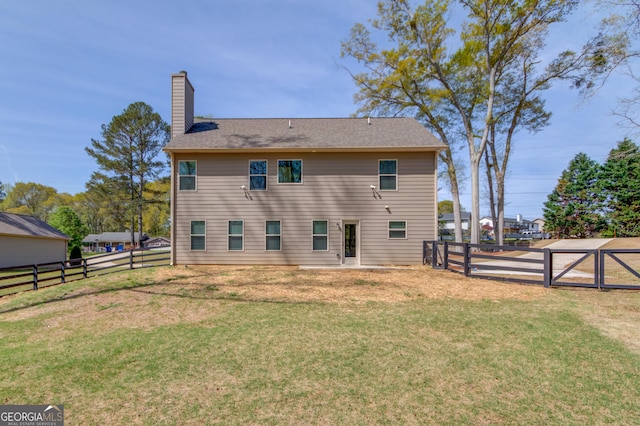 back of property with a fenced backyard, a gate, a yard, and a chimney
