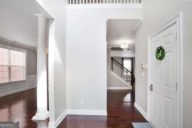 entrance foyer with wood finished floors, stairway, ornate columns, baseboards, and wainscoting