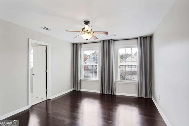 spare room with baseboards, ceiling fan, visible vents, and wood finished floors