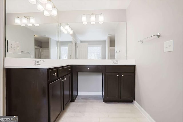 full bath featuring double vanity, a sink, and baseboards