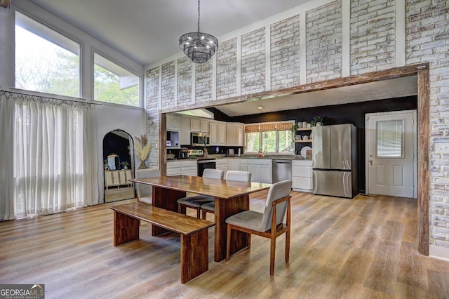 dining area featuring a high ceiling, arched walkways, and light wood-style floors