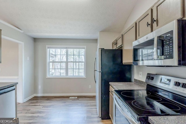 kitchen featuring a textured ceiling, light wood finished floors, baseboards, and appliances with stainless steel finishes