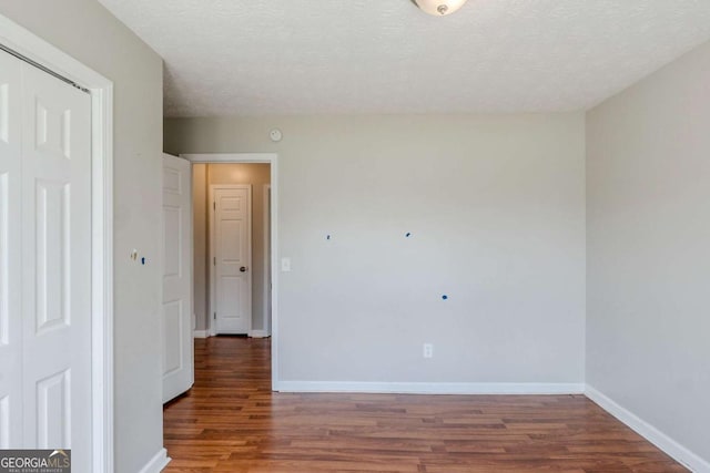 unfurnished room with baseboards, a textured ceiling, and wood finished floors