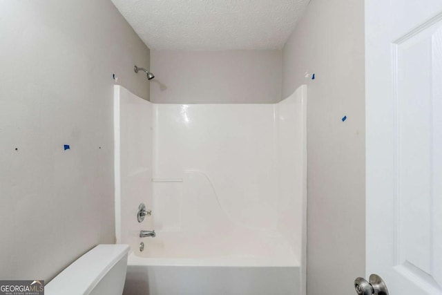 full bath with toilet, shower / bath combination, and a textured ceiling